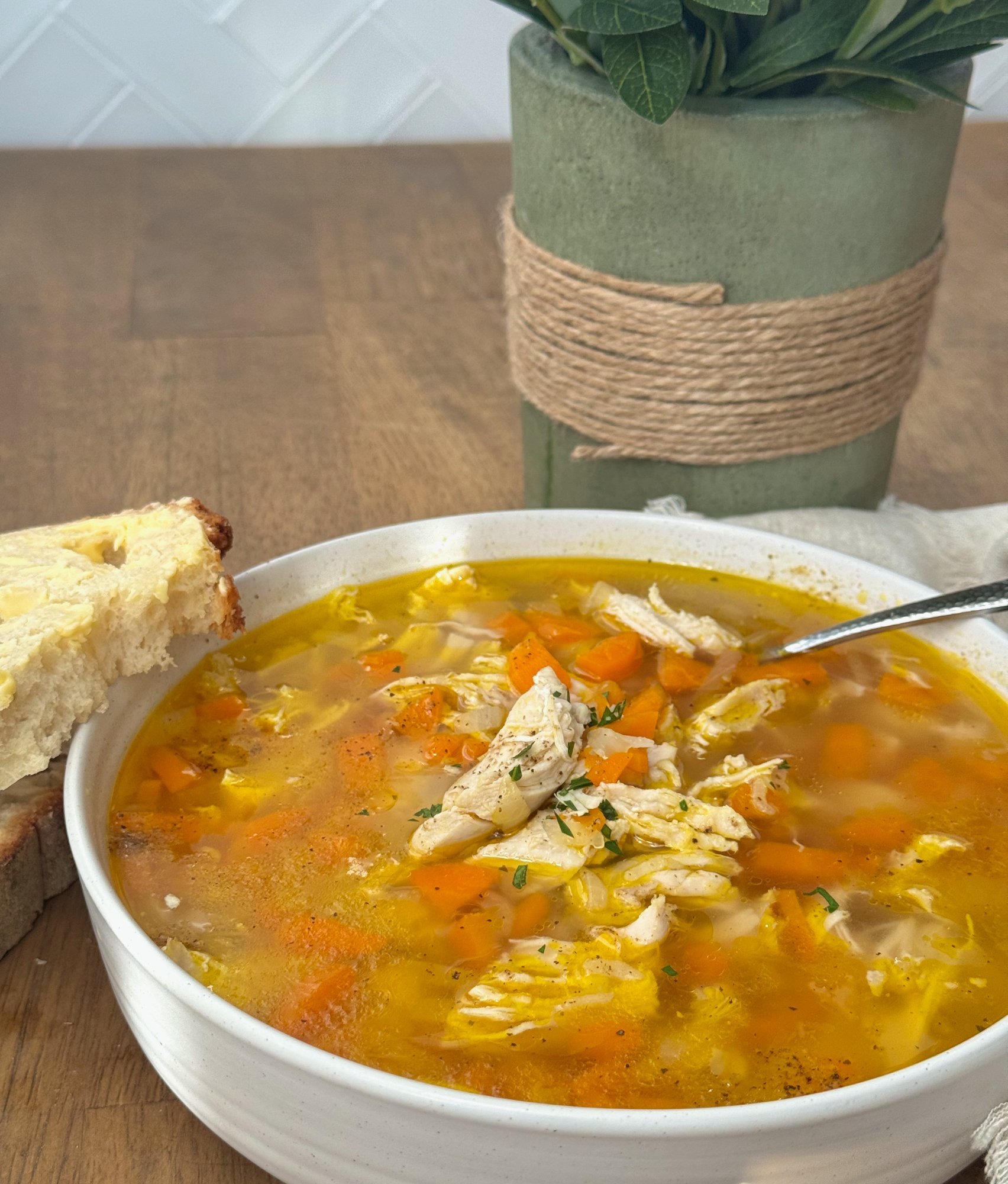 A bowl of golden chicken and rice soup with shredded chicken and carrot.