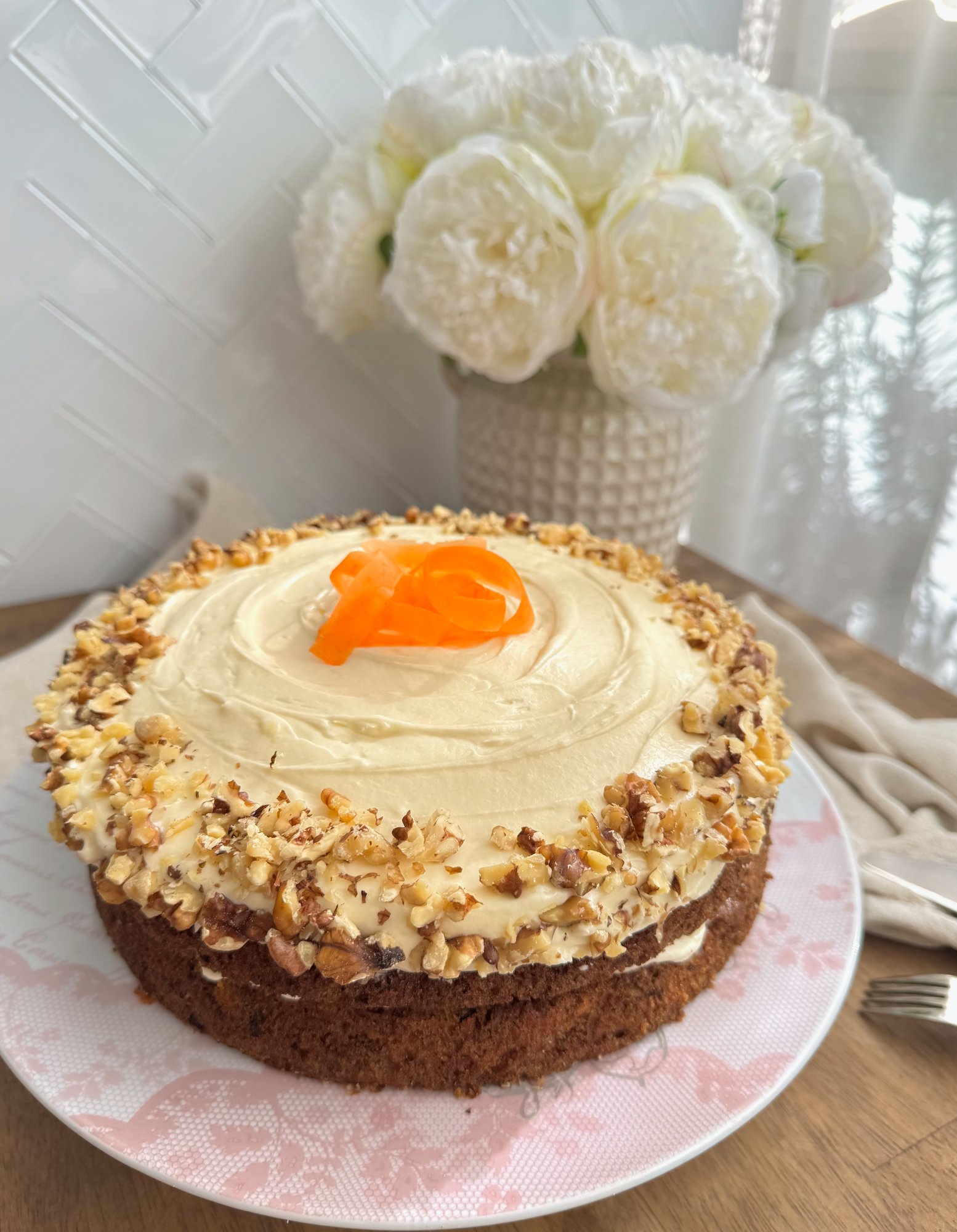 Carrot cake with thick cream cheese frosting, topped with walnuts and pecans.