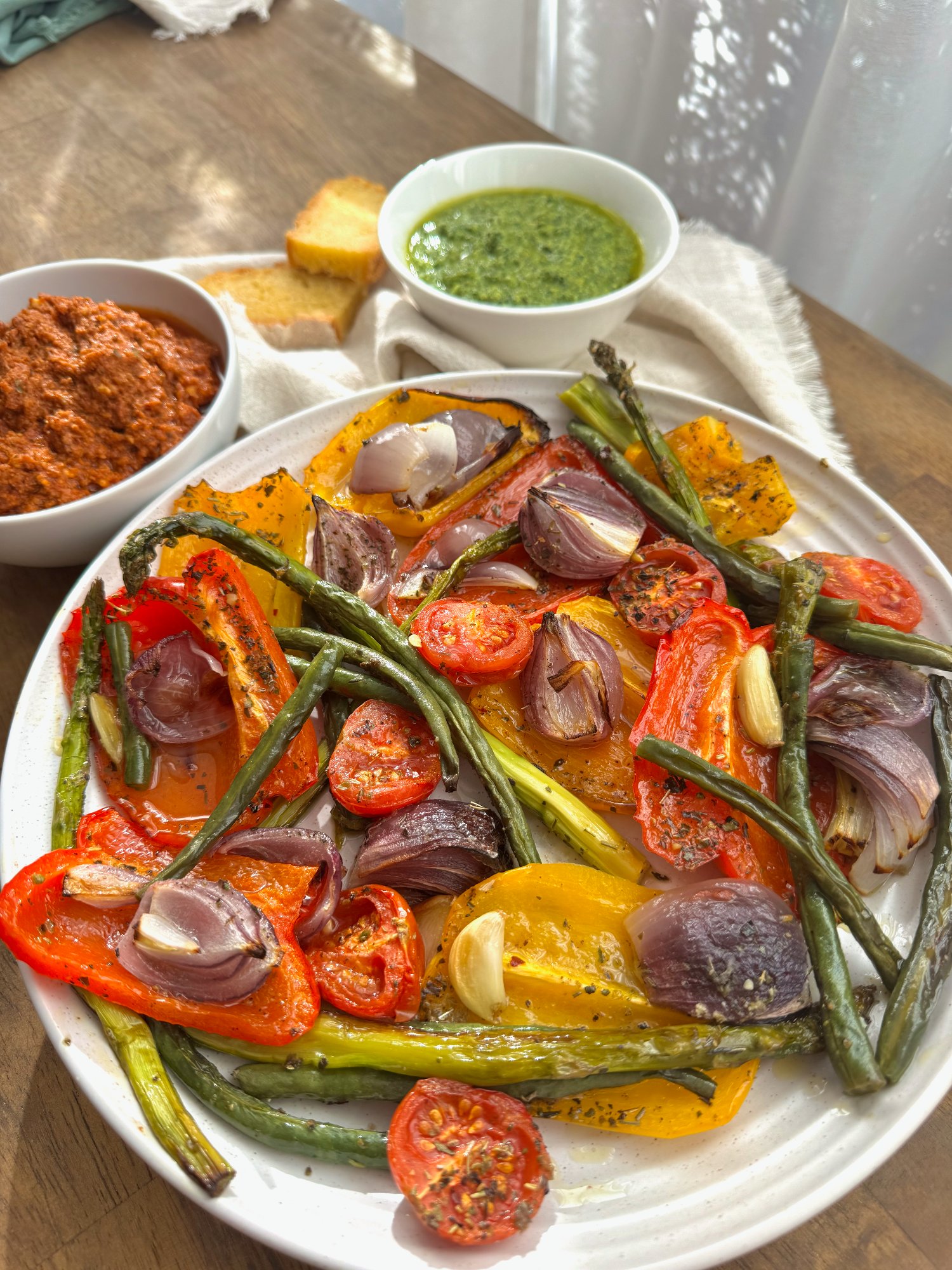 A platter of roasted capsicum, asparagus, green beans, tomatoes, red onion and garlic.