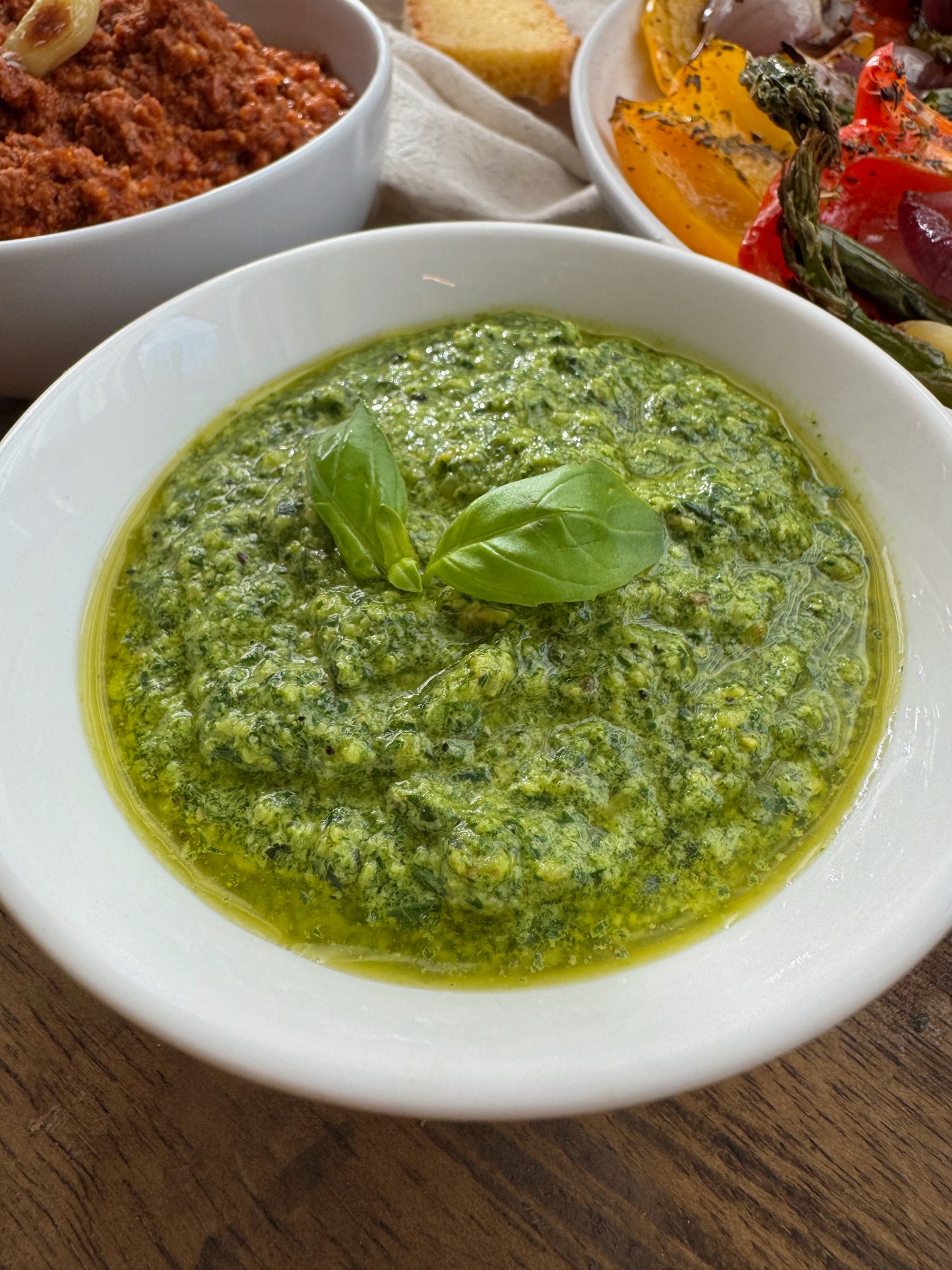 A bowl of thick, bright green dairy-free basil pesto.