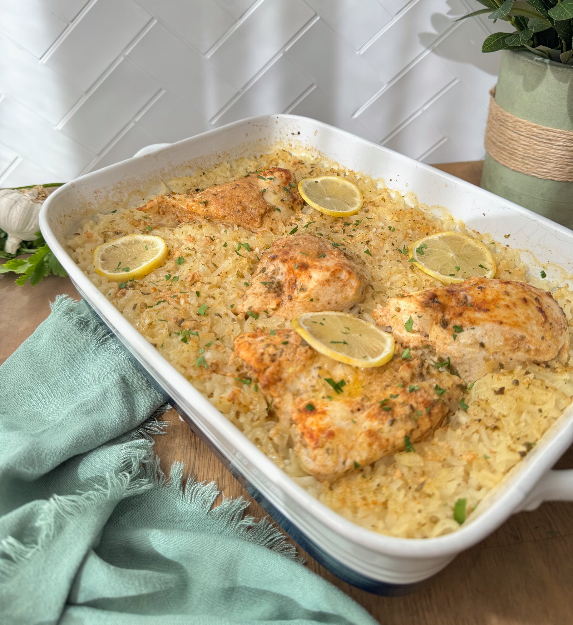 Chicken breast baked over lemon garlic rice in one pan with lemon slices and herbs.
