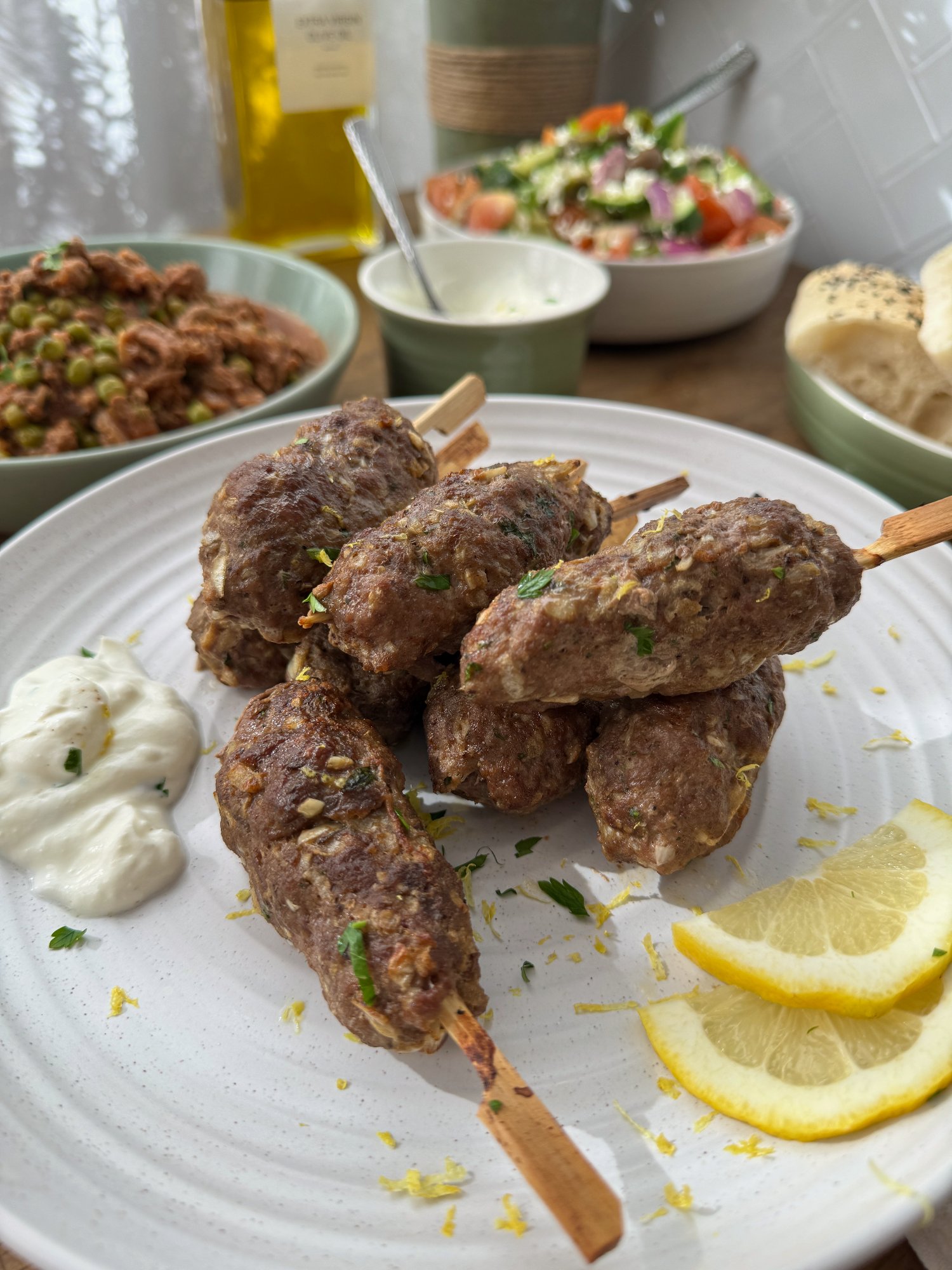 Golden lamb kofta skewers with yoghurt sauce, lemon and Greek-style salad.