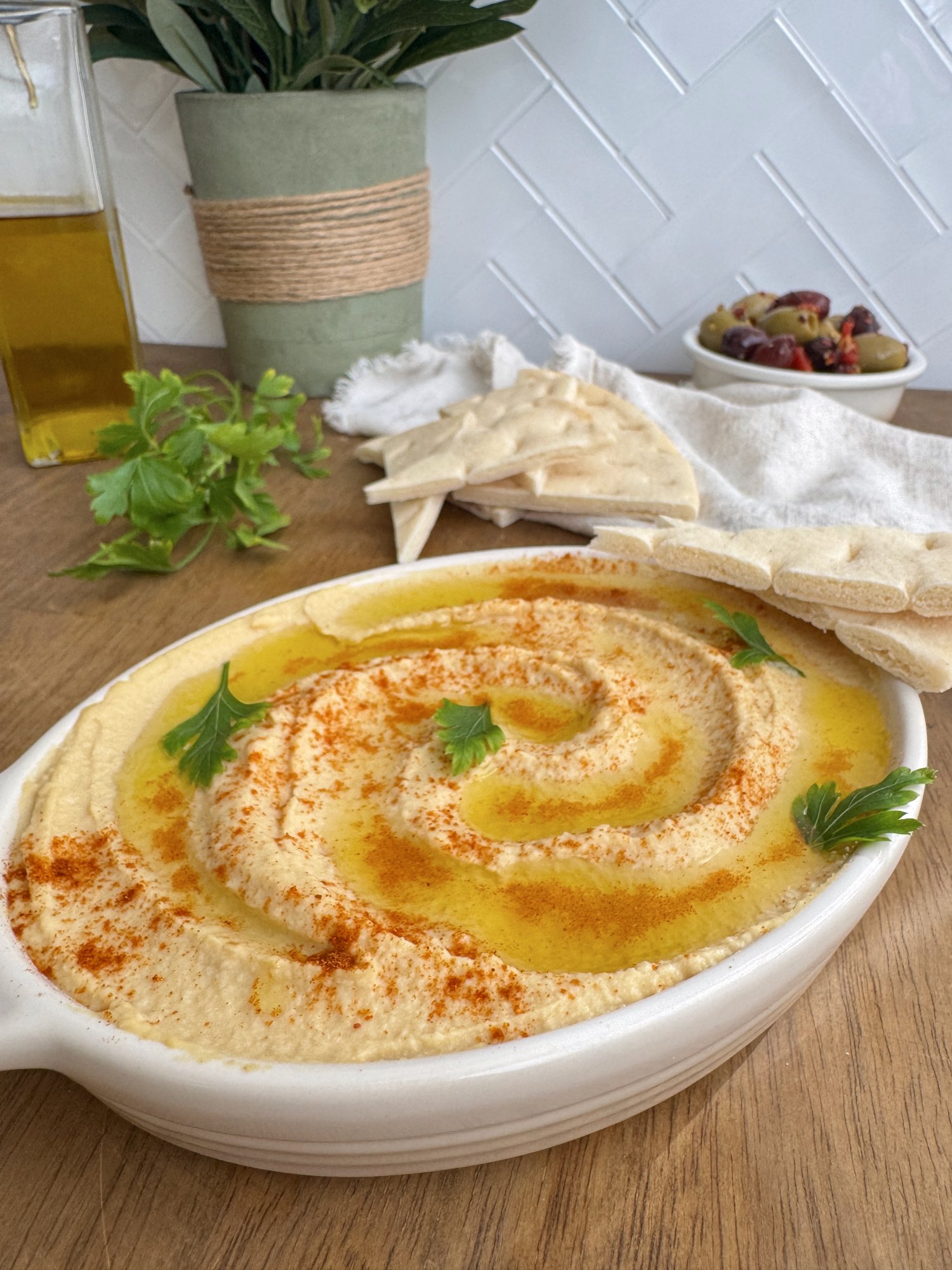 A bowl of smooth, creamy hummus swirled with olive oil.