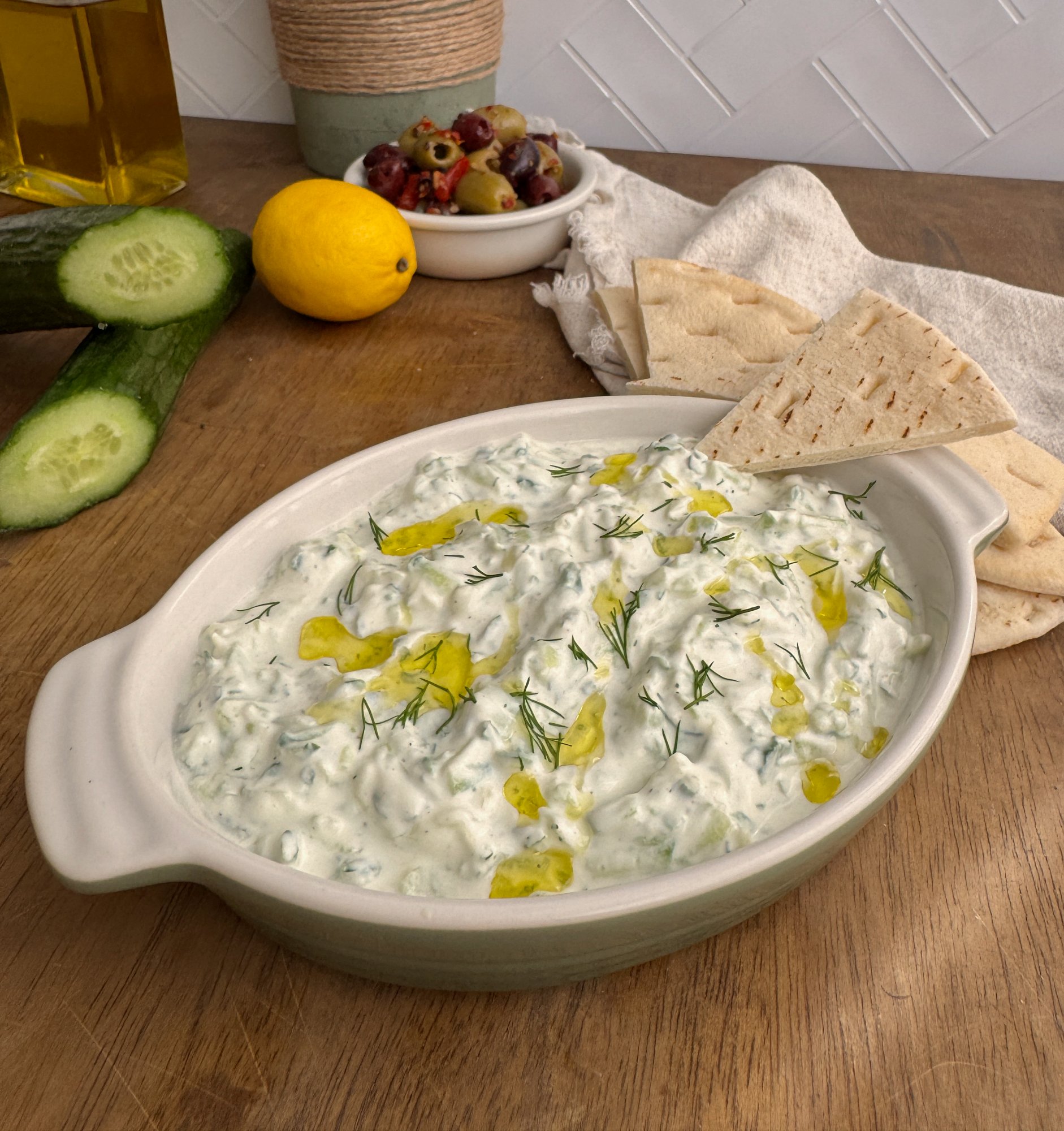 A bowl of thick tzatziki with grated cucumber, dill and olive oil.