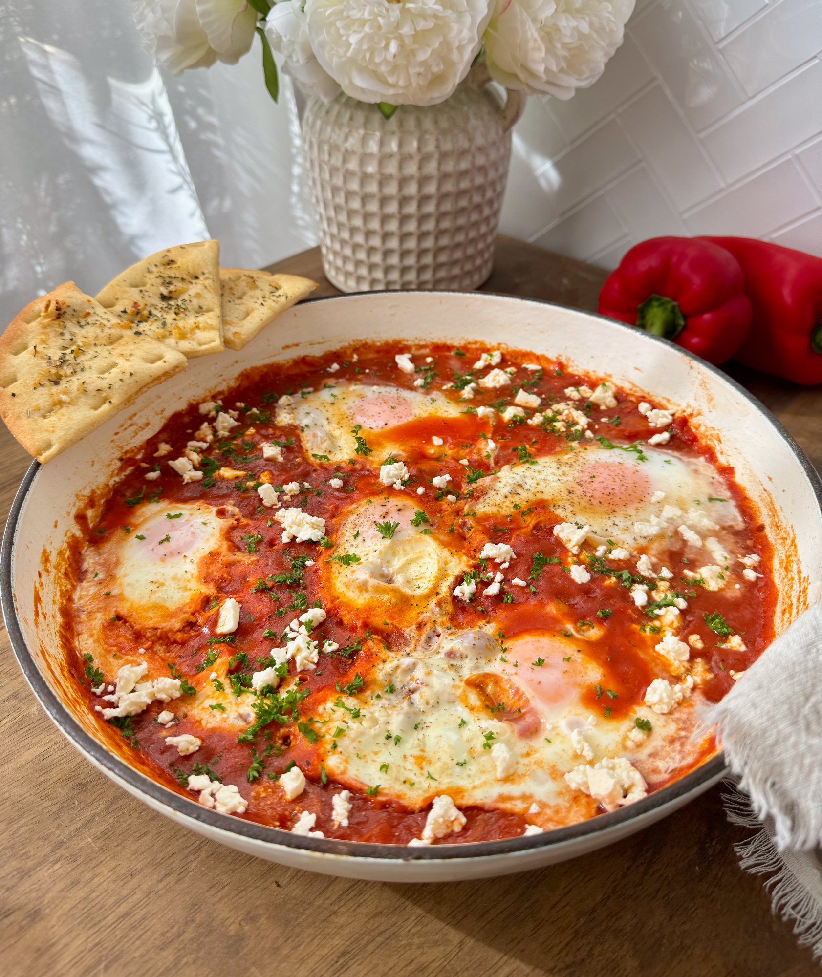 Shakshuka with soft-set eggs in a tomato and sweet pepper sauce, topped with crumbled feta.