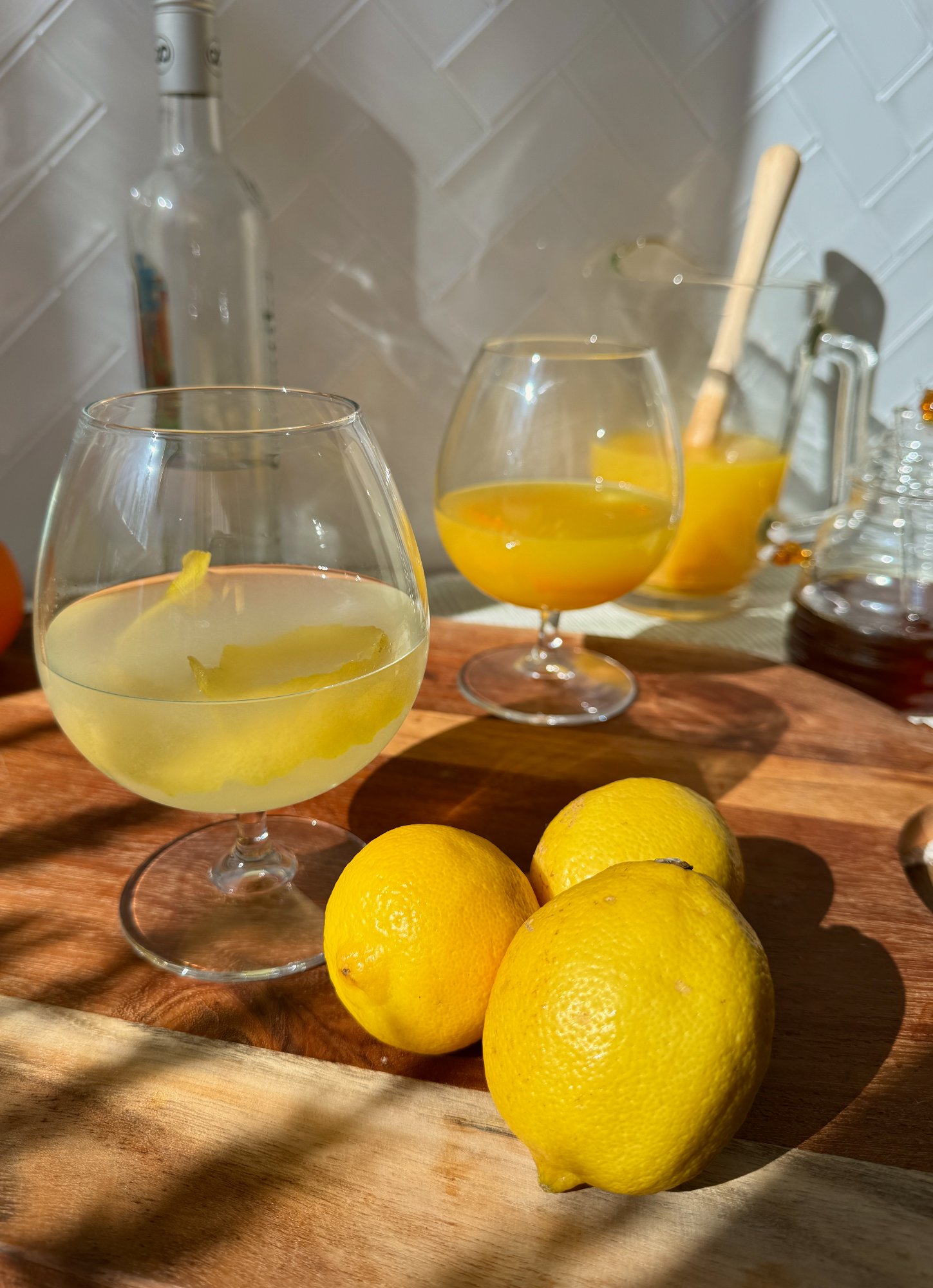 Two glasses of Madeira poncha, a traditional citrus drink, with lemon and orange.