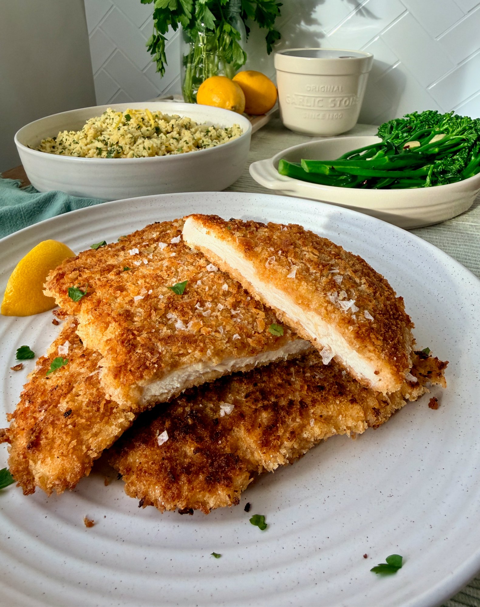 Golden, crisp chicken breast schnitzel with a panko crumb and a lemon wedge.