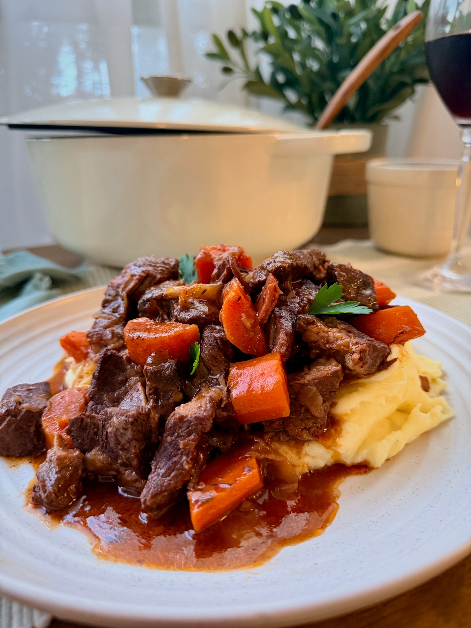 Beef bourguignon with tender beef, bacon and carrot in a glossy red wine sauce over mashed potato.