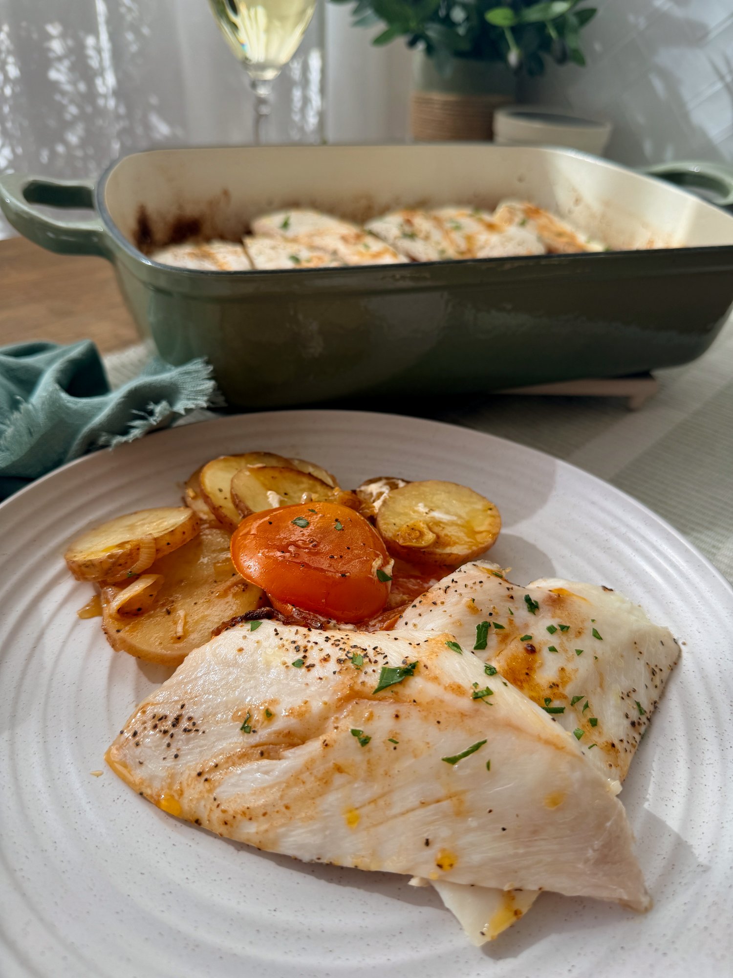 Portuguese-style baked snapper over sliced potatoes, onion and tomato in a baking dish.