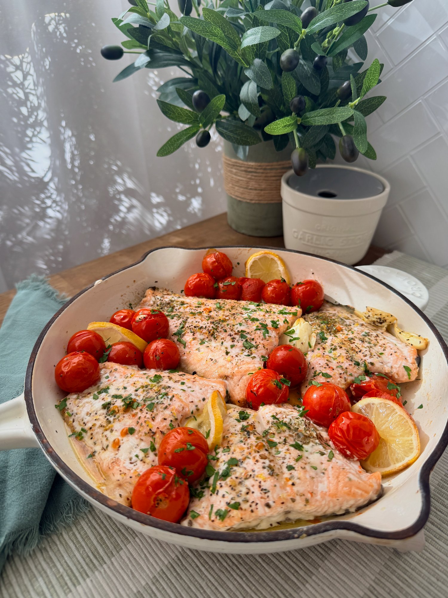 Baked salmon with blistered cherry tomatoes, lemon slices and fresh herbs.