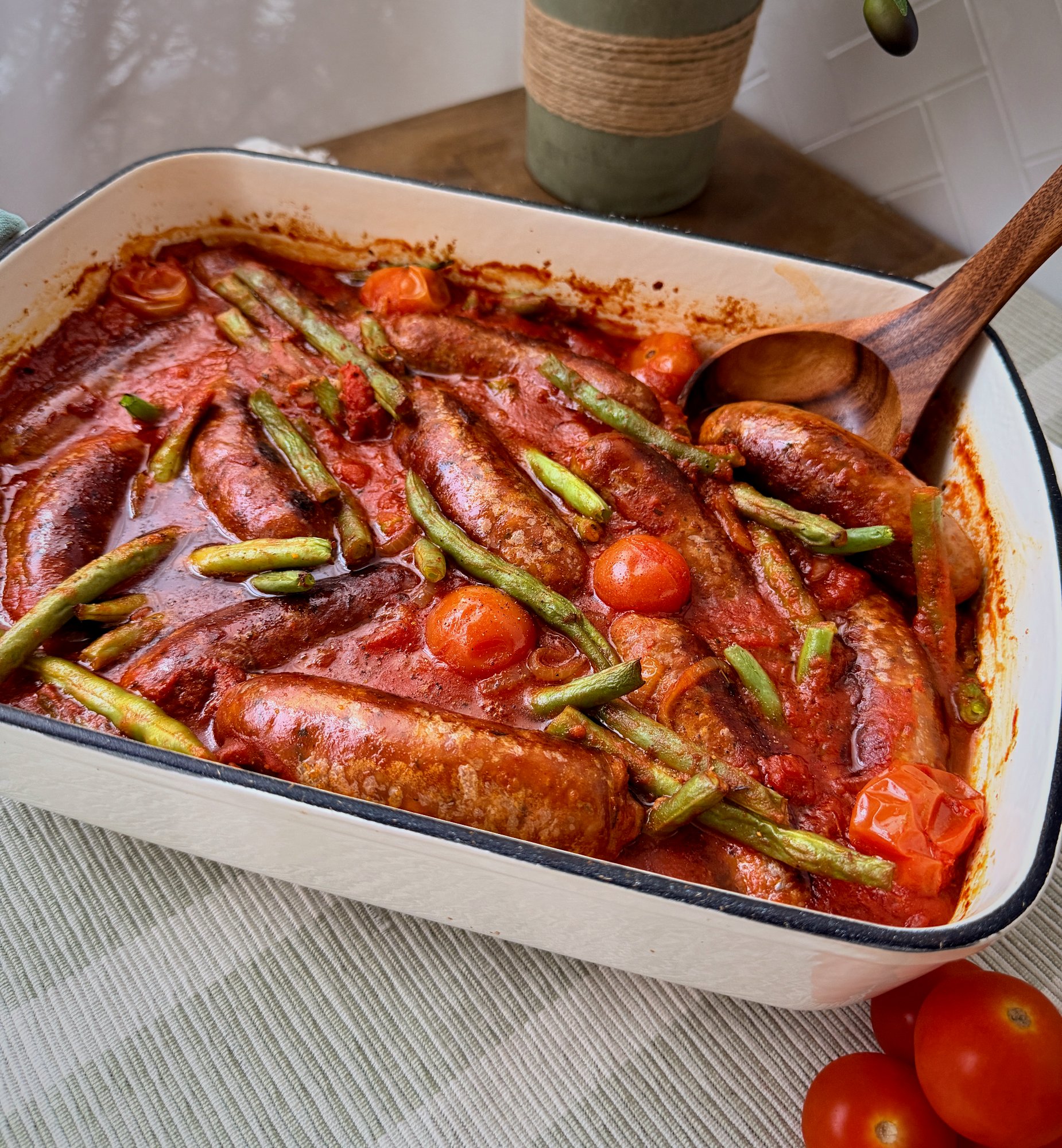 Pork and chorizo sausages baked with green beans and cherry tomatoes in a tomato sauce.
