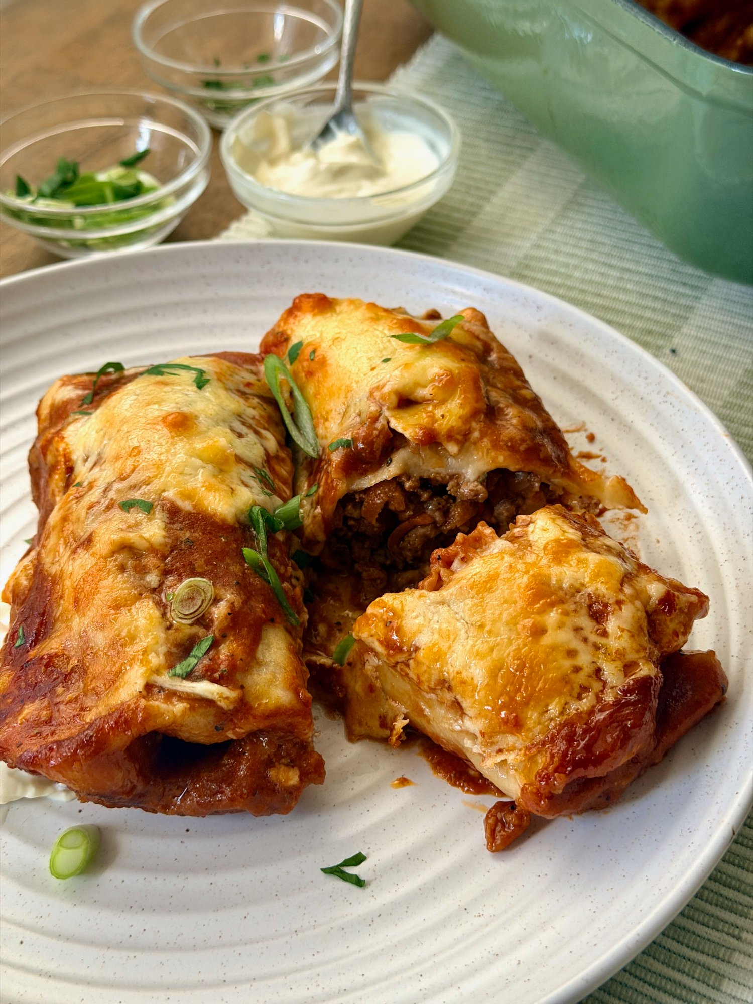 A baking dish of beef enchiladas under golden, bubbling melted cheese.