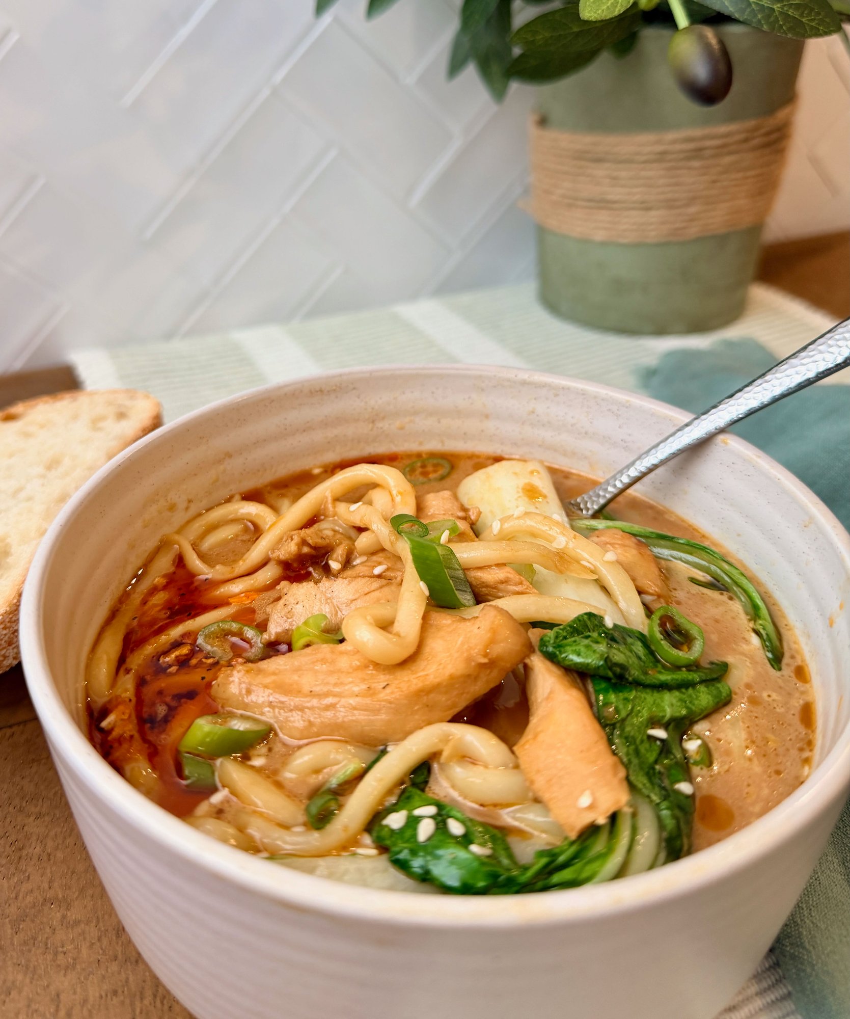 Creamy chilli chicken udon soup with thick noodles and bok choy.