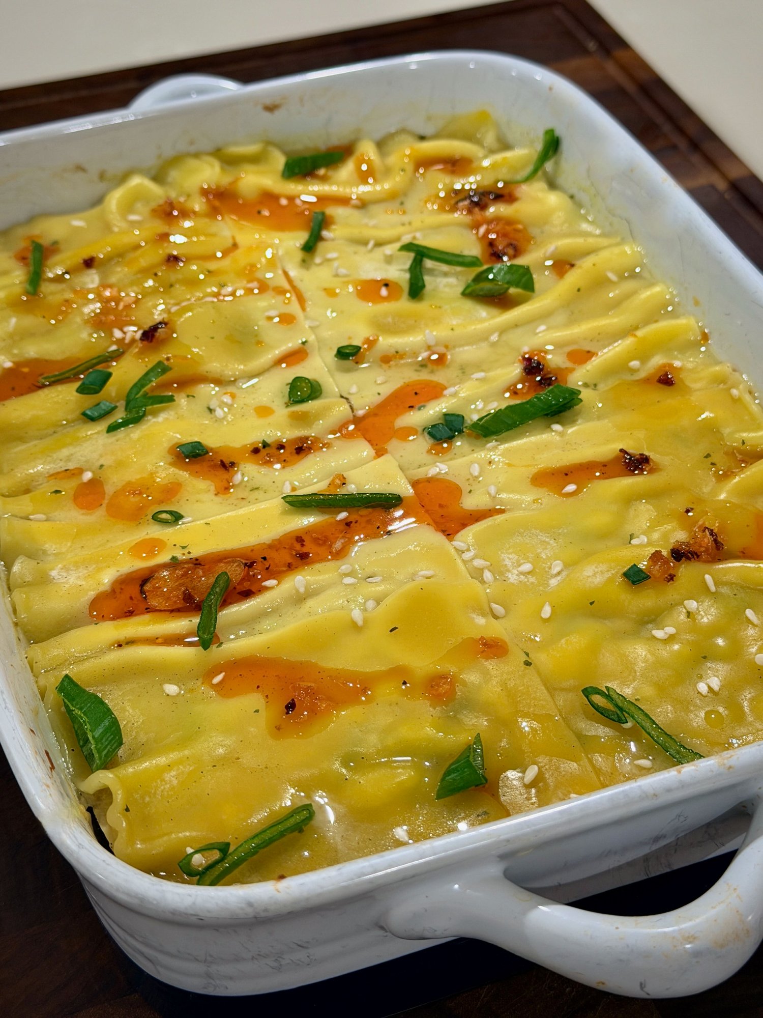 Baked chicken dumpling lasagna finished with chilli oil, spring onion and sesame seeds.