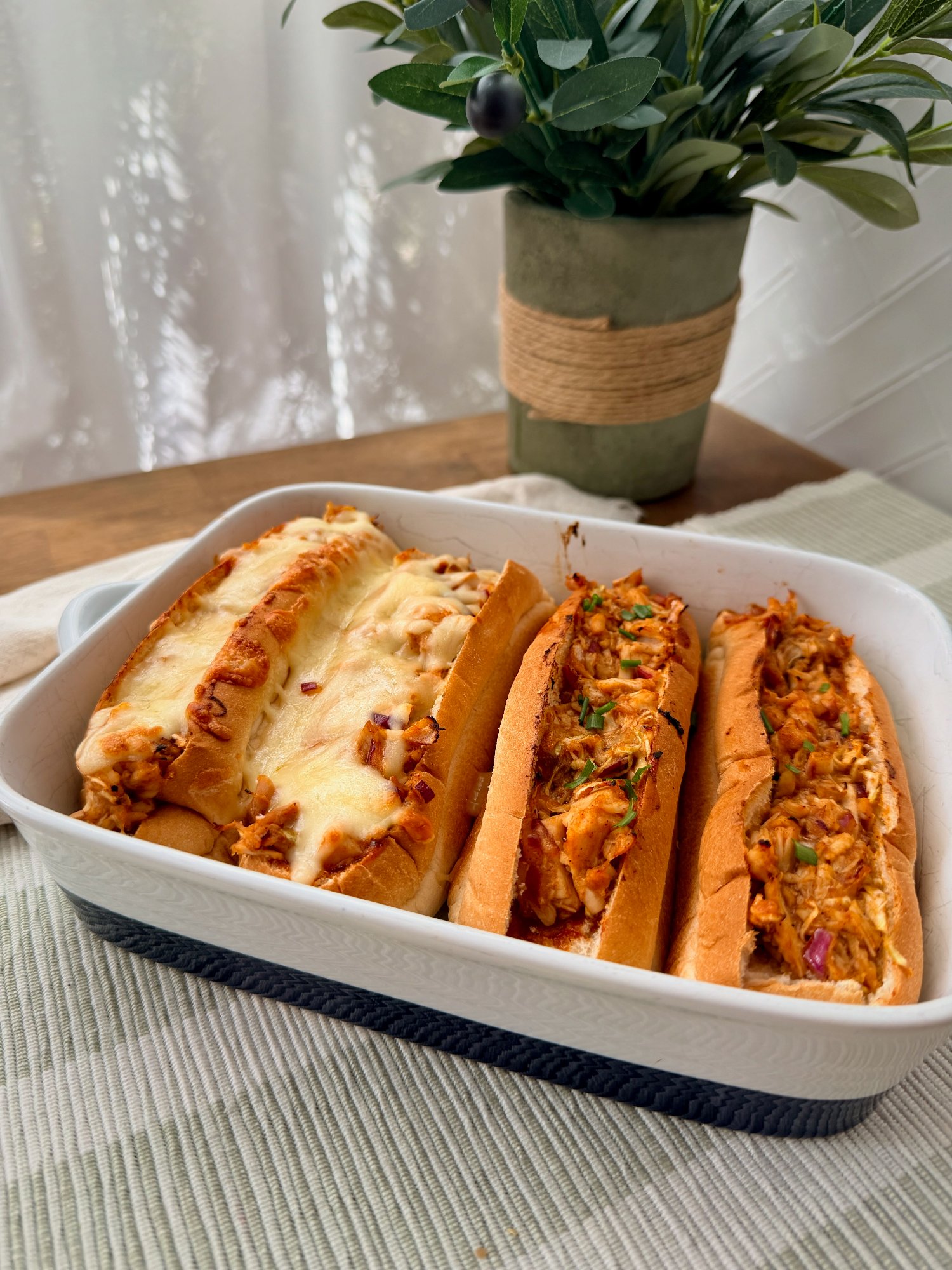 Cheesy BBQ chicken sliders with shredded cabbage, baked until golden.