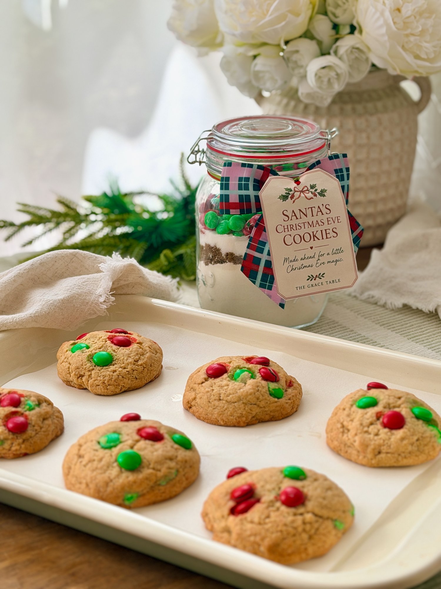 Santa's Christmas Eve Cookies on a cream tray, with the layered cookie jar, tartan ribbon and gift tag behind.