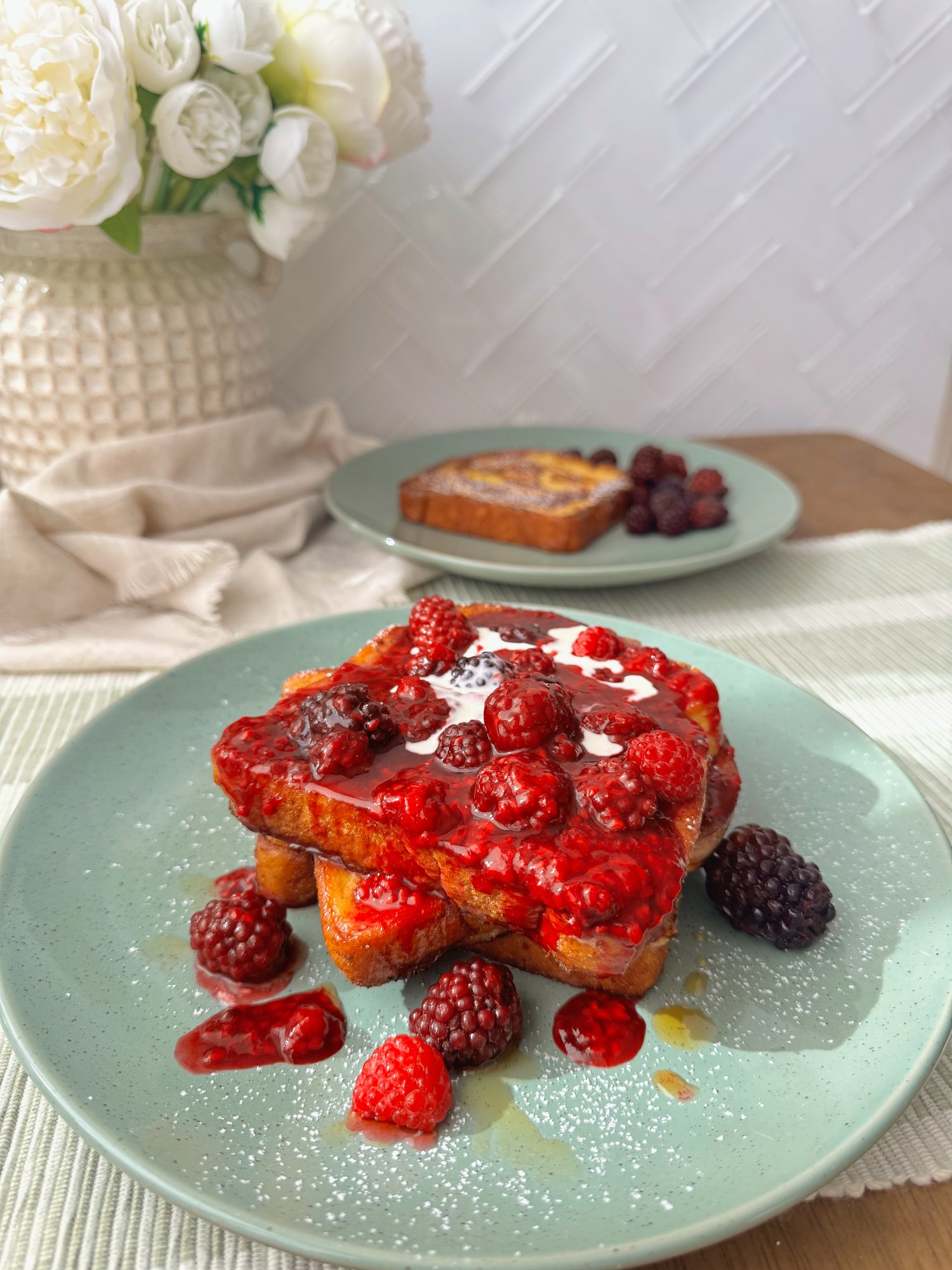 Golden French toast topped with warm raspberries, blackberries, maple syrup and icing sugar.
