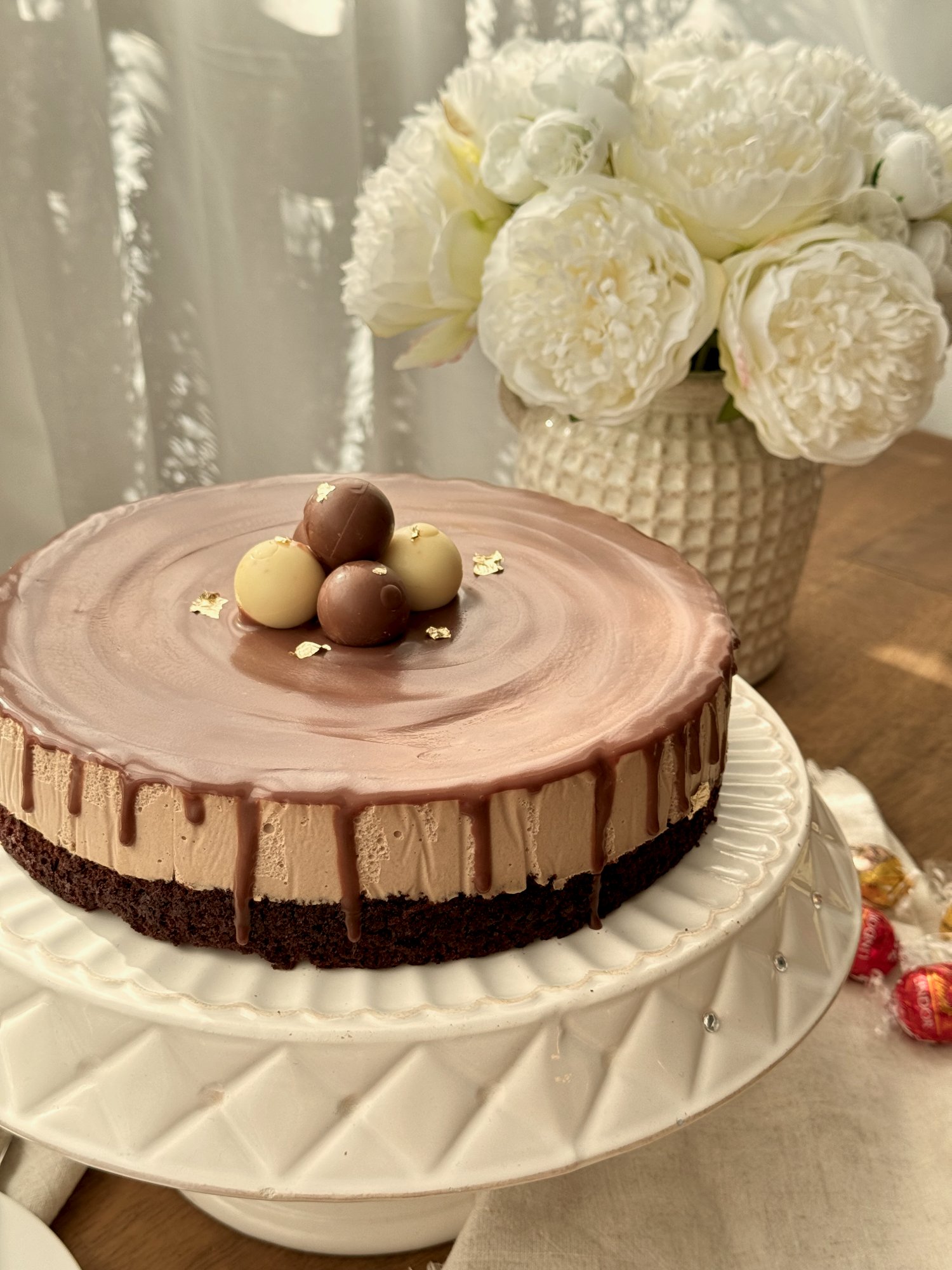 Lindt chocolate cheesecake cake with a glossy chocolate ganache top and Lindt chocolate balls.