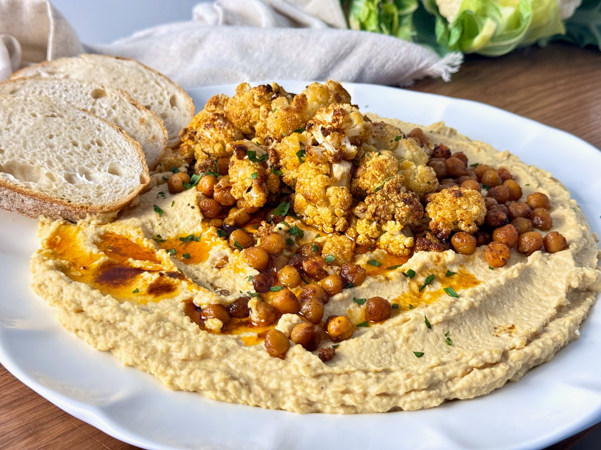 Roasted cauliflower and chickpeas over creamy hummus, drizzled with red peri peri oil.