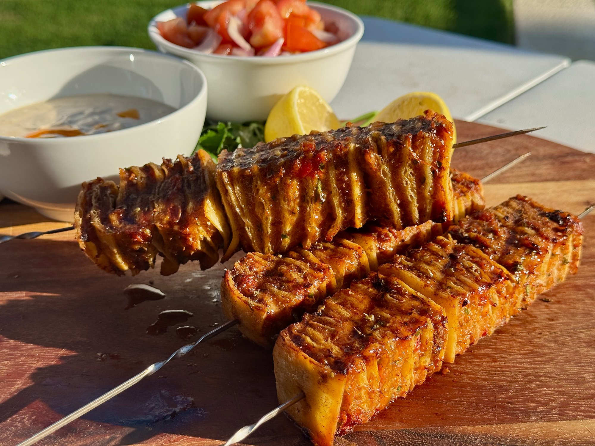Portuguese peri peri chicken tortilla kebab skewers with golden edges, served with tomato salad and yoghurt.
