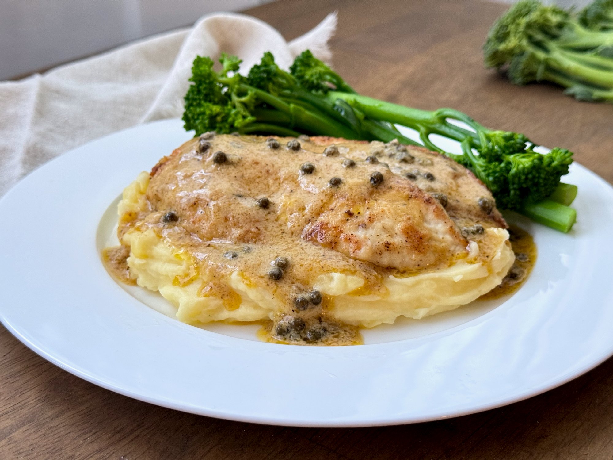 Chicken in a creamy green peppercorn sauce over mashed potato with broccolini.