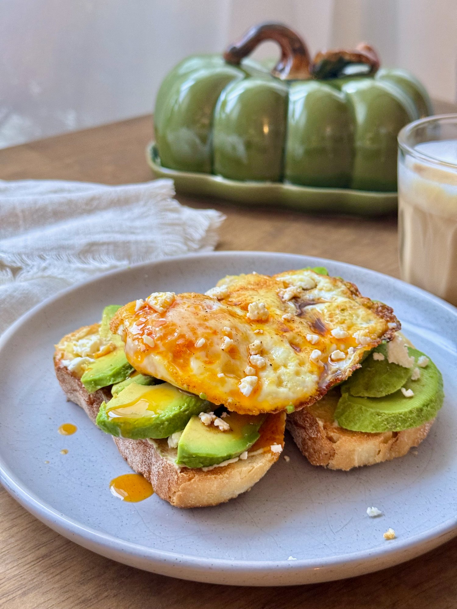 Avocado toast on thick pane di casa with a fried egg, crumbled feta and peri peri oil.